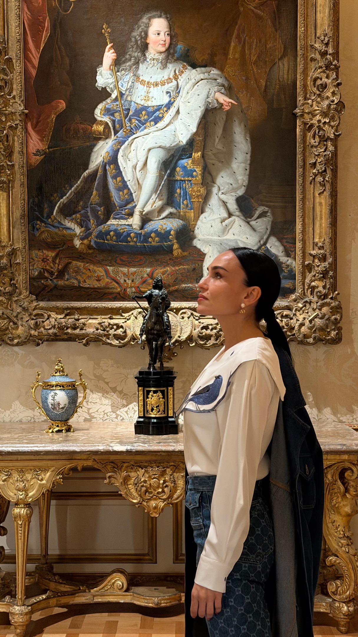 Galina at The Met in New York beside an ornate gilded table, porcelain and a portrait in a gold frame
