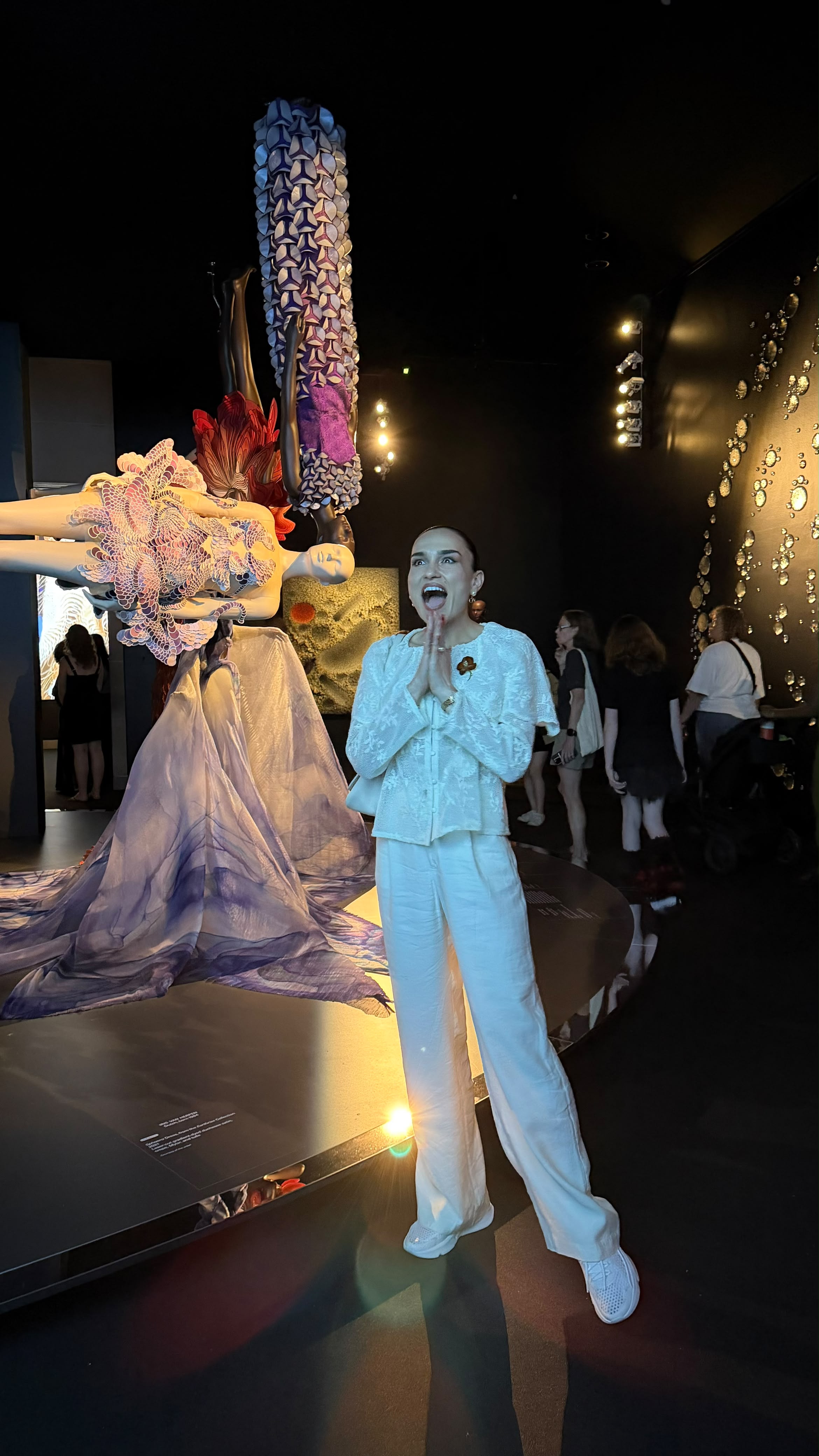 Galina reacting with delight beside Iris van Herpen designs at Brooklyn Museum