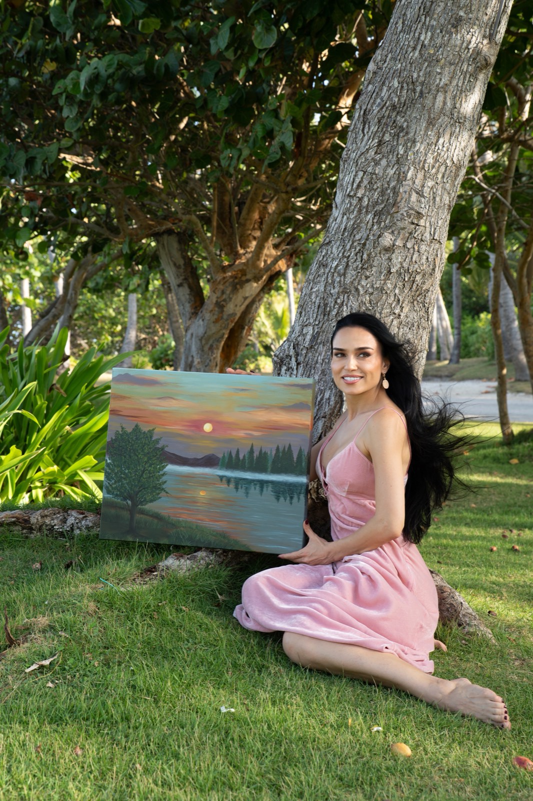 Galina seated beneath a tree with her sunset painting