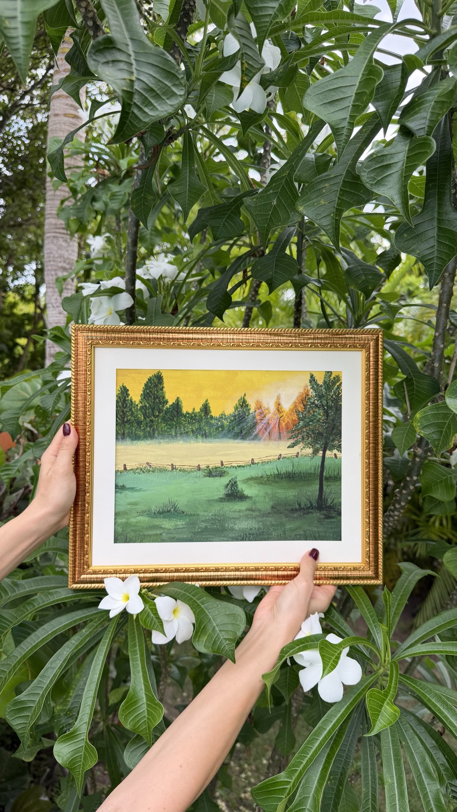 Framed green meadow and golden sky painting among leaves