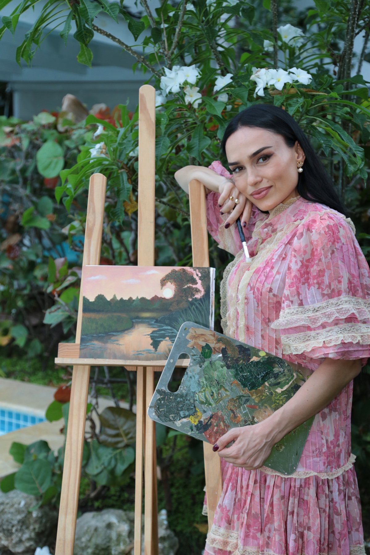 Galina at an outdoor easel with Reflection of Silence, a winding river beneath a pink evening sky